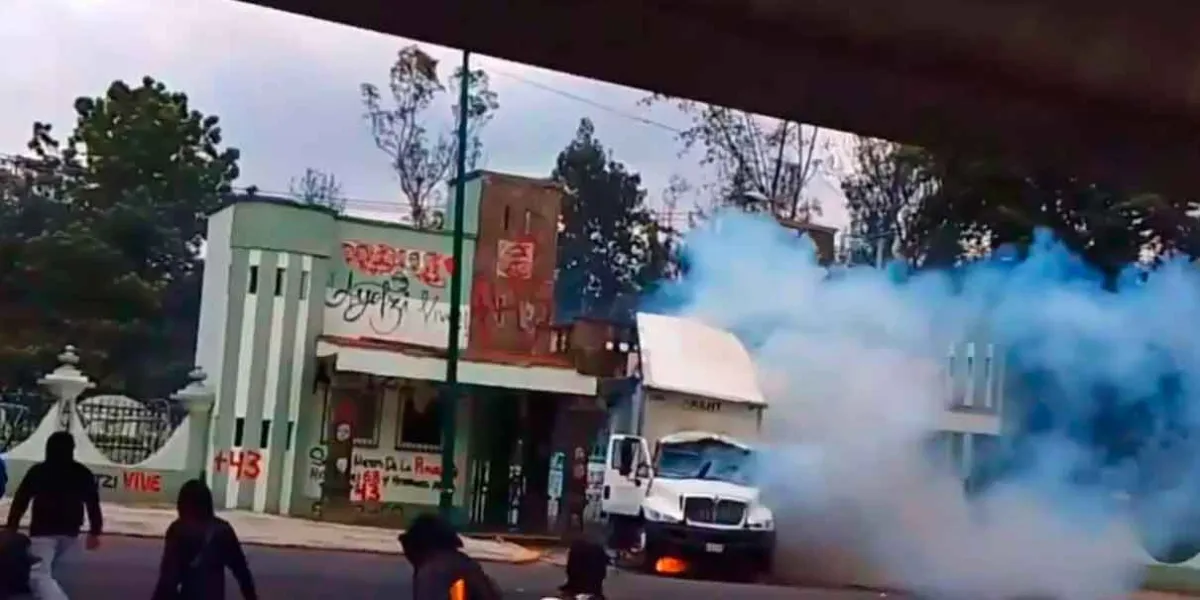 Normalistas de Ayotzinapa derriban puerta del Campo Militar 1-A y queman camión 